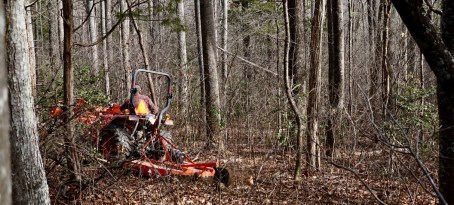 man on Kubota tractor with bush hog in woods