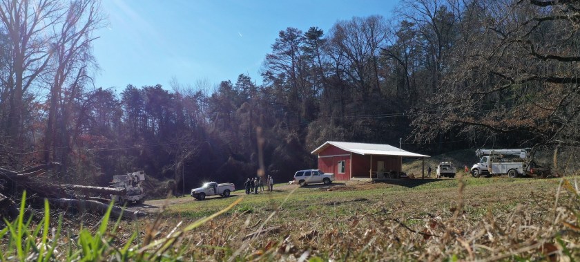 red barn home with power workers