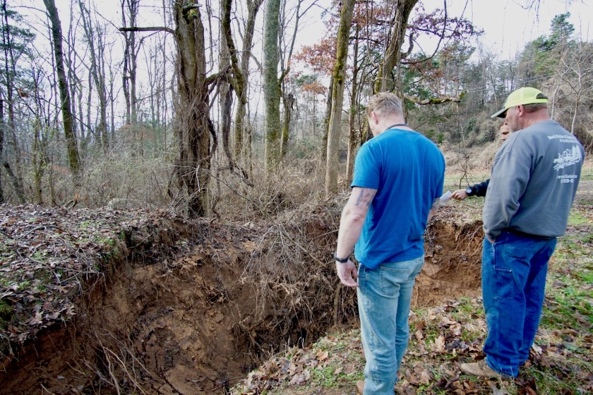 men standing on edge of sinkhole