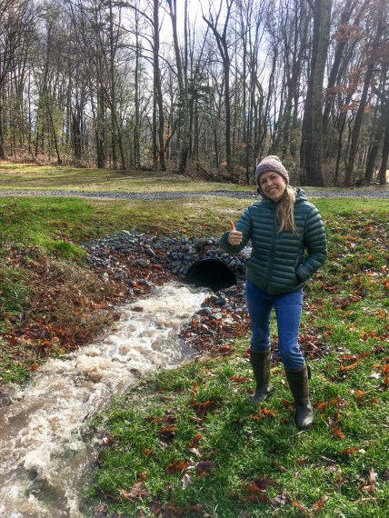 woman by creek running into a conduit